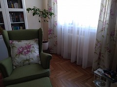 Pohodový obývací pokoj s květinovým designem závěsů, římských rolet a polštářů