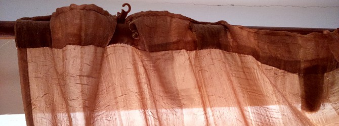 Výhled na horská úbočí rámovaný nedbale instalovanými záclonami
